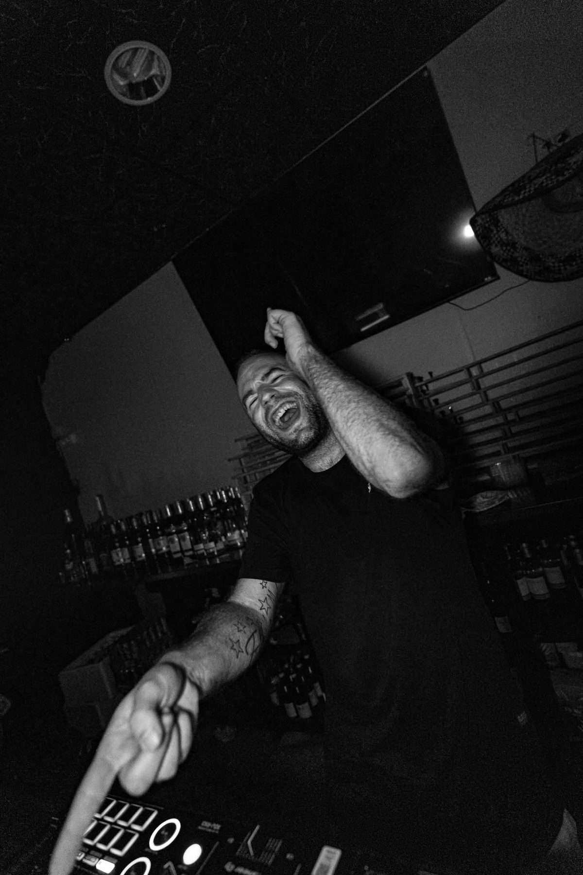 Portrait noir et blanc de JeremieV aux platines dans un bar